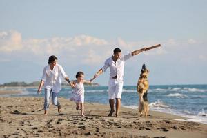 happy family playing with dog on beach photo