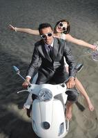 just married couple on the beach ride white scooter photo