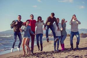 young friends jumping together at autumn beach photo