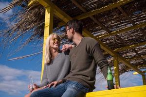 pareja joven bebiendo cerveza juntos en la playa foto