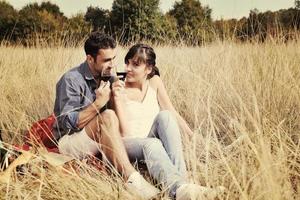 pareja feliz disfrutando de un picnic en el campo en hierba larga foto