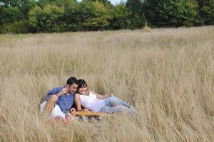 pareja feliz disfrutando de un picnic en el campo en hierba larga foto