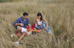 happy couple enjoying countryside picnic in long grass photo