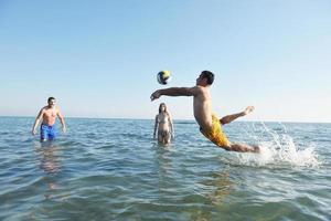 grupo de jóvenes divertirse y jugar voleibol de playa foto