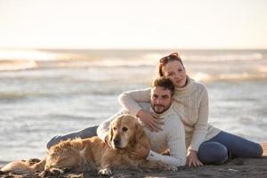 pareja con perro disfrutando del tiempo en la playa foto