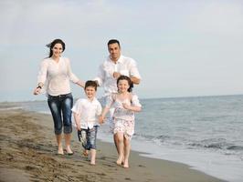 familia joven feliz divertirse en la playa foto