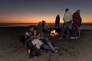 Couple enjoying bonfire with friends on beach photo