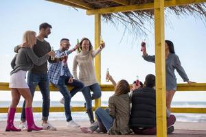 Group of friends having fun on autumn day at beach photo