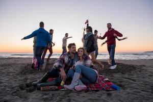 pareja disfrutando con amigos al atardecer en la playa foto