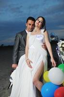 just married couple on the beach ride white scooter photo