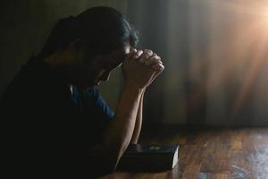 mano de persona de oración en fondo negro. la mujer católica cristiana está rezando a dios en la oscuridad en la iglesia. chica cree y fe en jesucristo. la religión de cristo y el cristianismo adoran o rezan concepto. foto