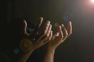 Prayer person hand in black background. Christian catholic woman are praying to god in dark at church. Girl believe and faith in jesus christ. Christ religion and christianity worship or pray concept. photo