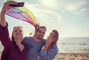 Group of friends making selfie on beach during autumn day photo