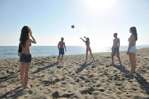 grupo de jóvenes divertirse y jugar voleibol de playa foto