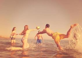 grupo de jóvenes divertirse y jugar voleibol de playa foto