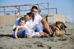 happy family playing with dog on beach photo