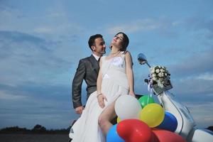 just married couple on the beach ride white scooter photo