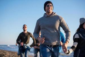 Group of friends running on beach during autumn day photo