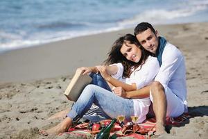 pareja joven disfrutando de un picnic en la playa foto