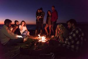 Couple enjoying with friends at sunset on the beach photo