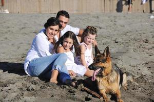 familia feliz jugando con el perro en la playa foto