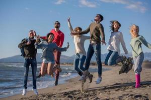 young friends jumping together at autumn beach photo