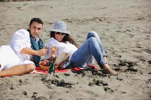 pareja joven disfrutando de un picnic en la playa foto