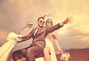 just married couple on the beach ride white scooter photo