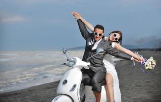 just married couple on the beach ride white scooter photo