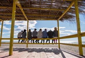 Group of friends having fun on autumn day at beach photo