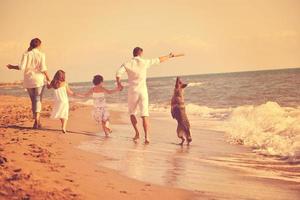 happy family playing with dog on beach photo