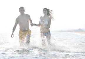 feliz pareja joven tiene tiempo romántico en la playa foto