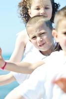 Grupo de niños felices jugando en la playa foto