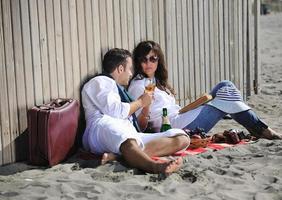 pareja joven disfrutando de un picnic en la playa foto