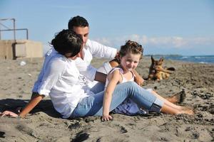 happy family playing with dog on beach photo