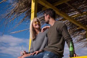 young couple drinking beer together at the beach photo