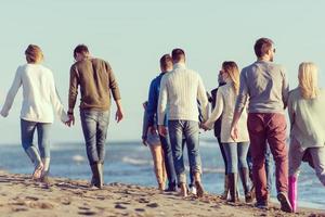 grupo de amigos corriendo en la playa durante el día de otoño foto