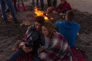 Couple enjoying bonfire with friends on beach photo