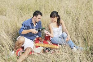 pareja feliz disfrutando de un picnic en el campo en hierba larga foto