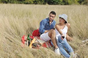 happy couple enjoying countryside picnic in long grass photo