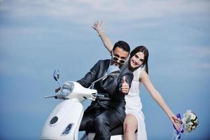 just married couple on the beach ride white scooter photo