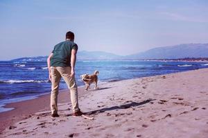 man with dog enjoying free time on the beach photo