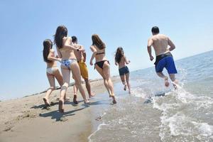 grupo de gente feliz divertirse y correr en la playa foto