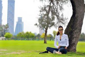 hermosa mujer joven con tableta en el parque foto