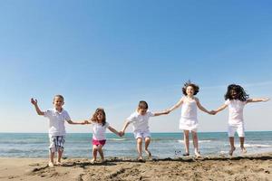 Grupo de niños felices jugando en la playa foto