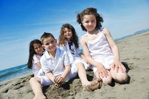 Grupo de niños felices jugando en la playa foto