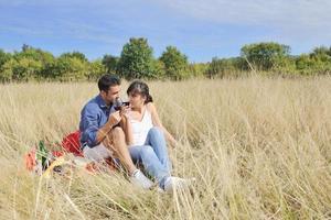 pareja feliz disfrutando de un picnic en el campo en hierba larga foto