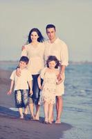 familia joven feliz divertirse en la playa al atardecer foto