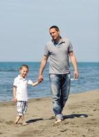 feliz padre e hijo se divierten y disfrutan del tiempo en la playa foto