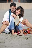 pareja joven disfrutando de un picnic en la playa foto